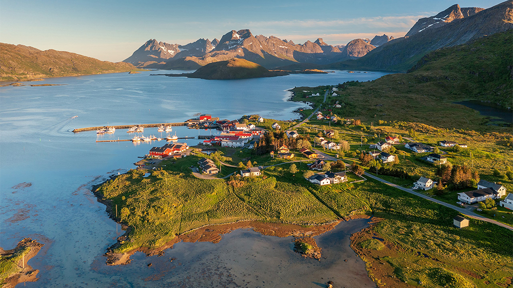 Dronebilde av lokalsmafunn med fjord og fjell