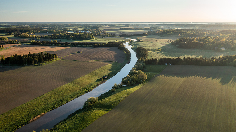 En elv som renner gjennom et jordbrukslandskap