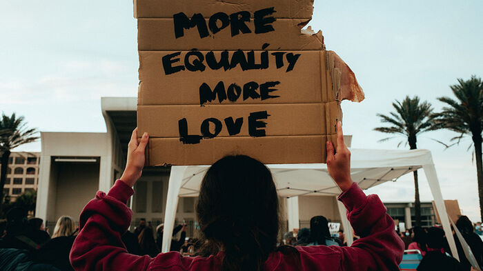 Demonstrator with a cardboard with the text  "MORE EQUALITY MORE LOVE"